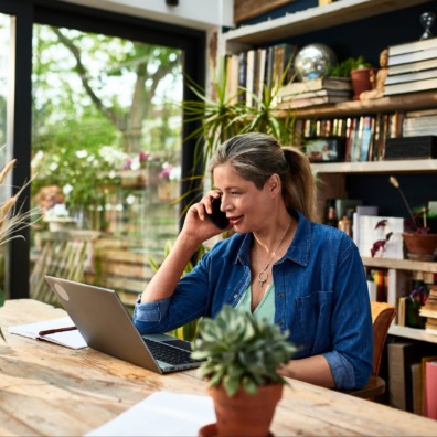 Businesswoman using mobile phone in front of laptop