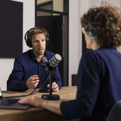 Man wearing headset talking with guest in recording studio